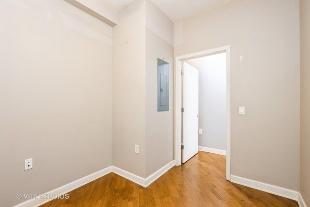 unfurnished room featuring light wood-style floors, baseboards, and electric panel