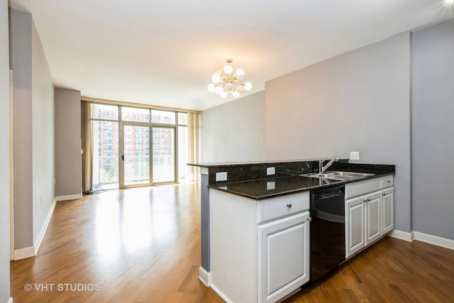 kitchen featuring dishwasher, a sink, a peninsula, dark wood-type flooring, and baseboards