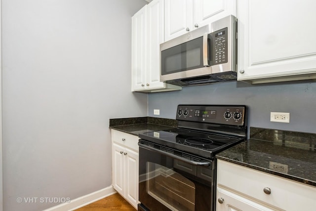 kitchen with stainless steel microwave, electric range, white cabinetry, and baseboards