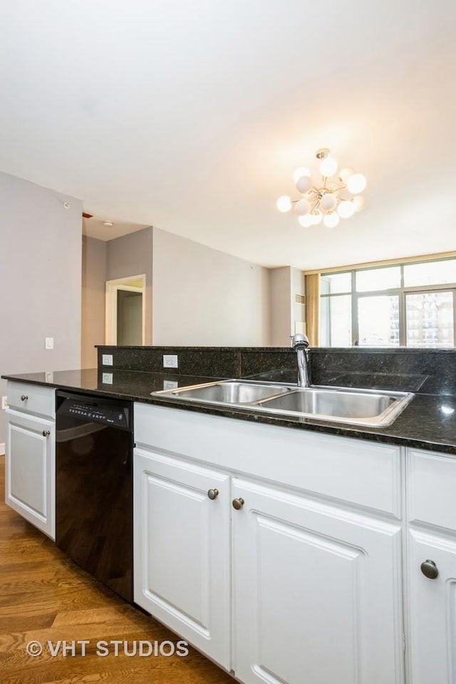 kitchen featuring dishwasher, a sink, a chandelier, wood finished floors, and white cabinets