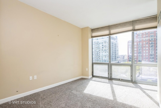 unfurnished room with a view of city, carpet, baseboards, and floor to ceiling windows