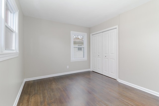 unfurnished bedroom featuring a closet, wood finished floors, and baseboards