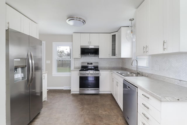 kitchen featuring a sink, tasteful backsplash, white cabinetry, light countertops, and appliances with stainless steel finishes