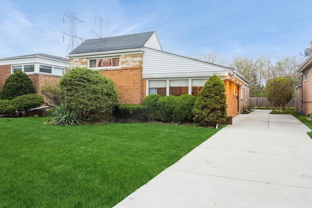 view of front of property with concrete driveway, a front lawn, and brick siding