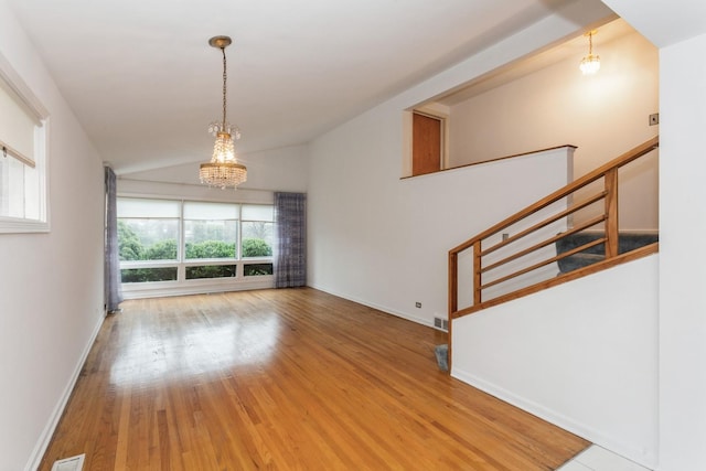 spare room featuring baseboards, lofted ceiling, wood finished floors, and a notable chandelier