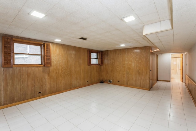 below grade area with light floors, wood walls, and visible vents