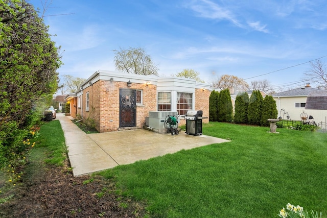 rear view of property with a patio, a yard, and brick siding