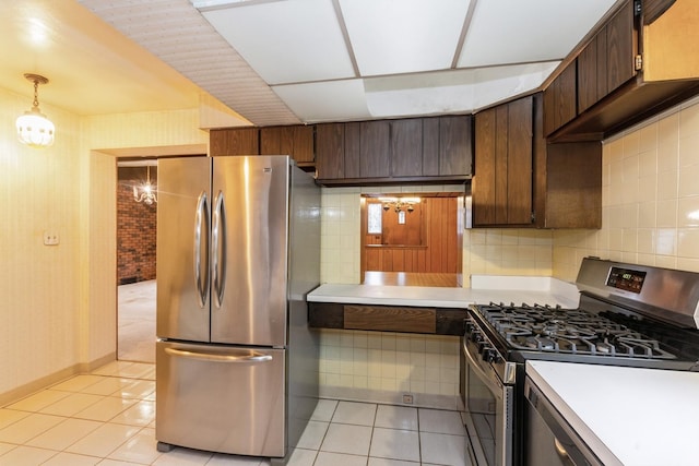 kitchen with light tile patterned flooring, dark brown cabinets, light countertops, tasteful backsplash, and appliances with stainless steel finishes