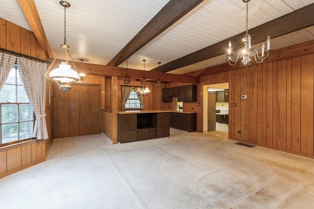 kitchen featuring wooden walls, a notable chandelier, beam ceiling, and visible vents