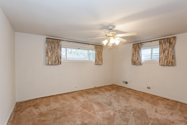 carpeted empty room with baseboards, a ceiling fan, and a wealth of natural light