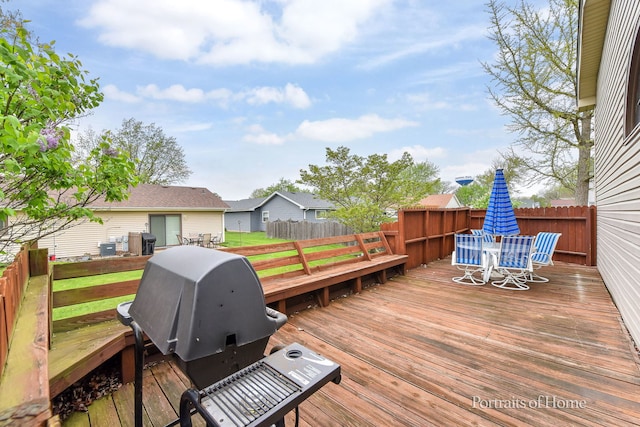 wooden deck featuring outdoor dining area, a grill, and fence