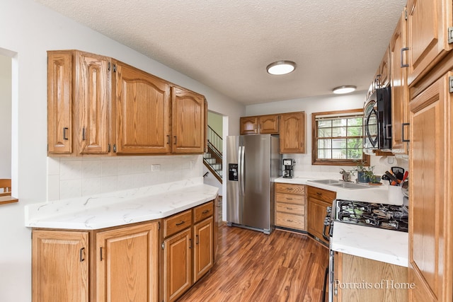 kitchen featuring light wood-style flooring, a sink, stainless steel refrigerator with ice dispenser, backsplash, and black microwave