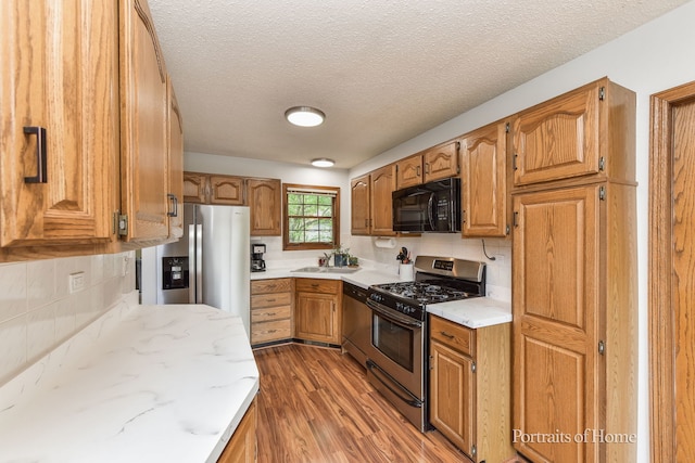 kitchen featuring backsplash, light wood-style floors, stainless steel appliances, and light stone counters