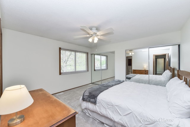 carpeted bedroom featuring a ceiling fan and multiple closets