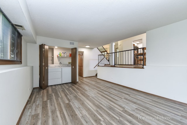 interior space featuring washer and dryer, light wood finished floors, visible vents, baseboards, and stairs