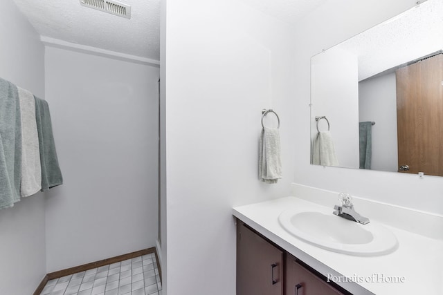 bathroom featuring vanity, a textured ceiling, visible vents, tile patterned floors, and baseboards