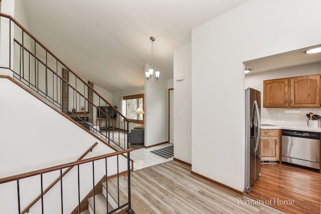 kitchen with stainless steel appliances, tasteful backsplash, a chandelier, light countertops, and light wood-style floors