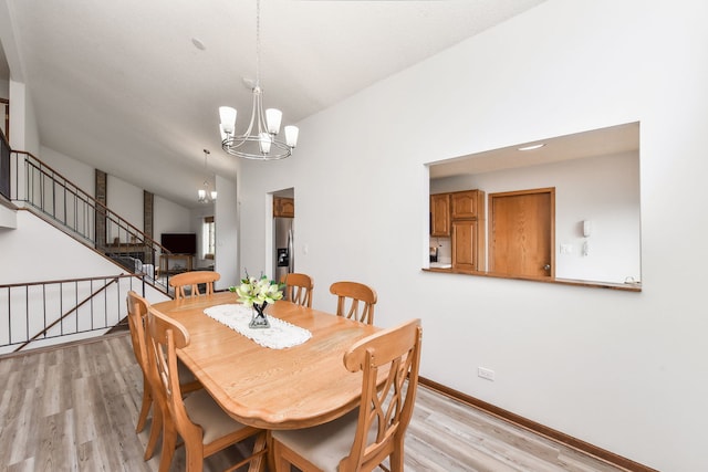 dining area with baseboards, stairs, light wood-style floors, and a chandelier