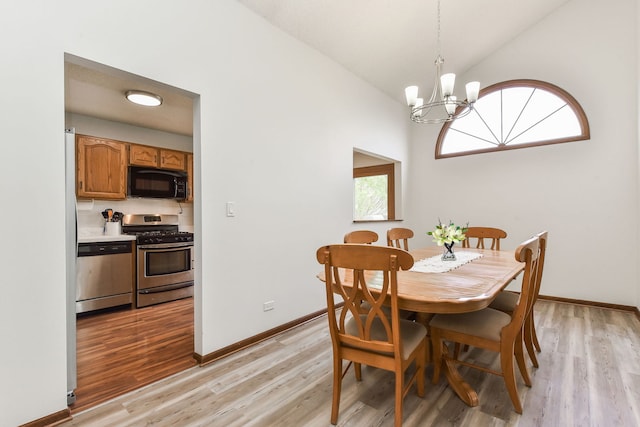 dining space with a chandelier, lofted ceiling, baseboards, and light wood-type flooring