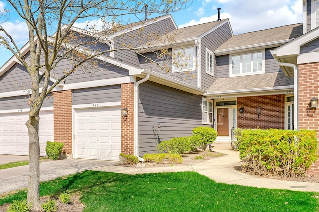 townhome / multi-family property featuring brick siding, a shingled roof, a front yard, and concrete driveway