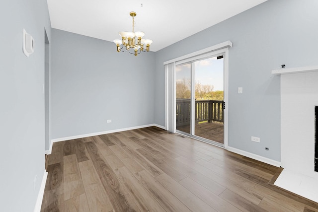 unfurnished dining area with baseboards, visible vents, wood finished floors, and a notable chandelier