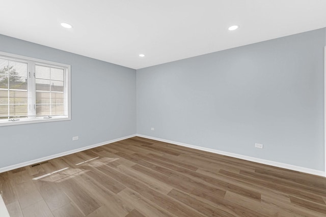 empty room featuring visible vents, recessed lighting, baseboards, and wood finished floors