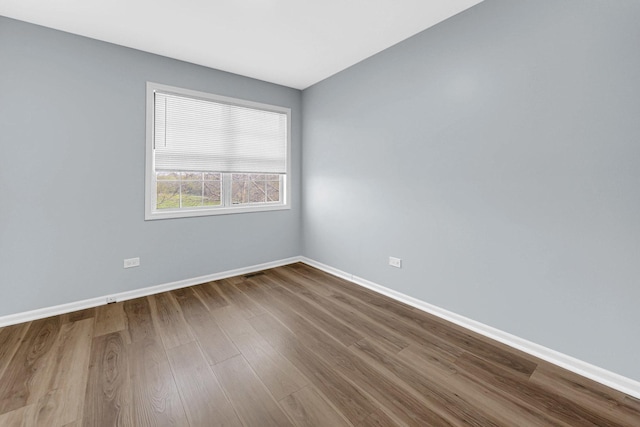 spare room featuring dark wood-style flooring and baseboards