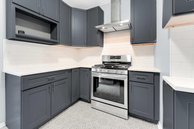 kitchen featuring light countertops, stainless steel gas range oven, wall chimney range hood, and tasteful backsplash
