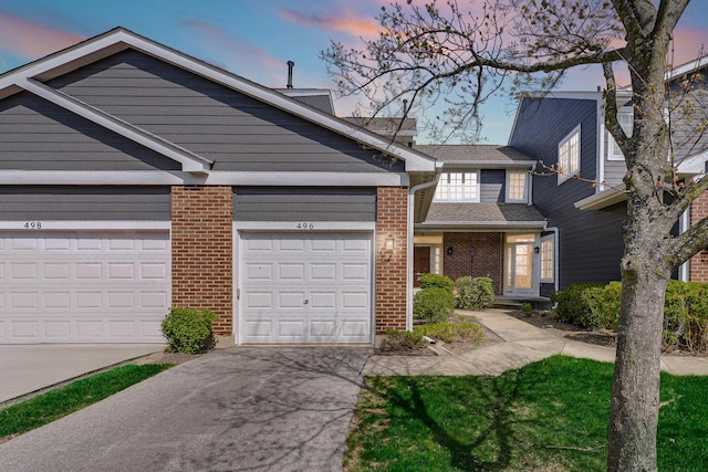 view of property with a garage, driveway, and brick siding