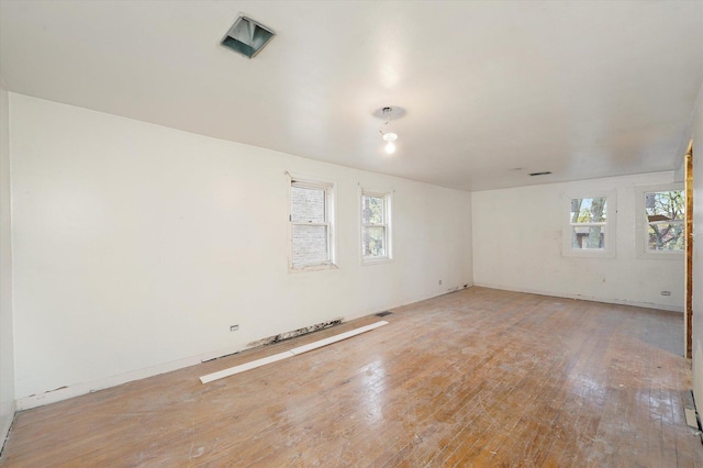 unfurnished room featuring light wood-style floors, visible vents, and baseboards