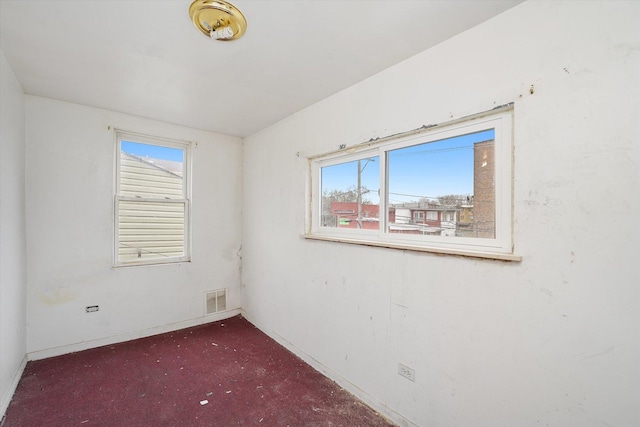 carpeted empty room with visible vents and baseboards