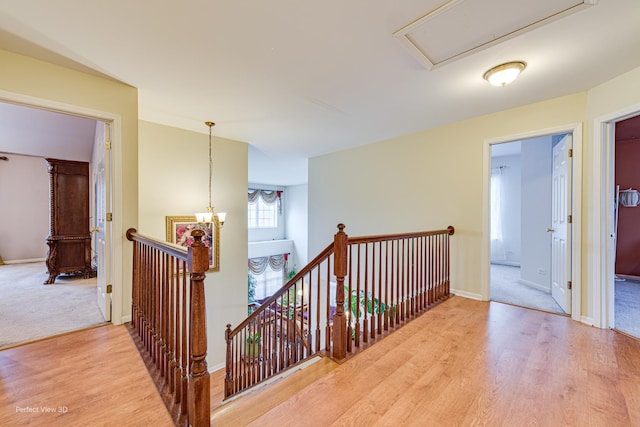 hall featuring an upstairs landing, baseboards, and light wood-type flooring