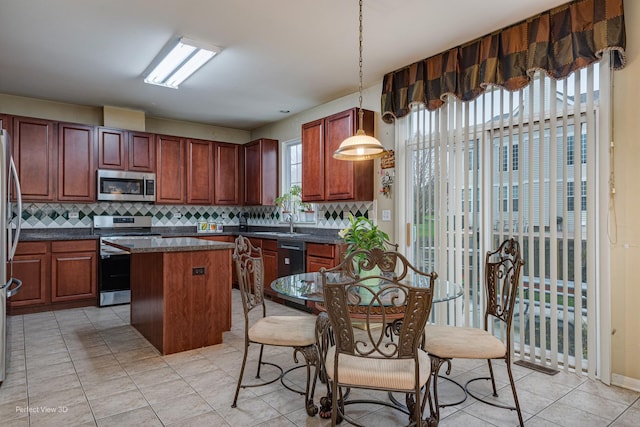 kitchen featuring decorative backsplash, light tile patterned floors, appliances with stainless steel finishes, a kitchen island, and pendant lighting