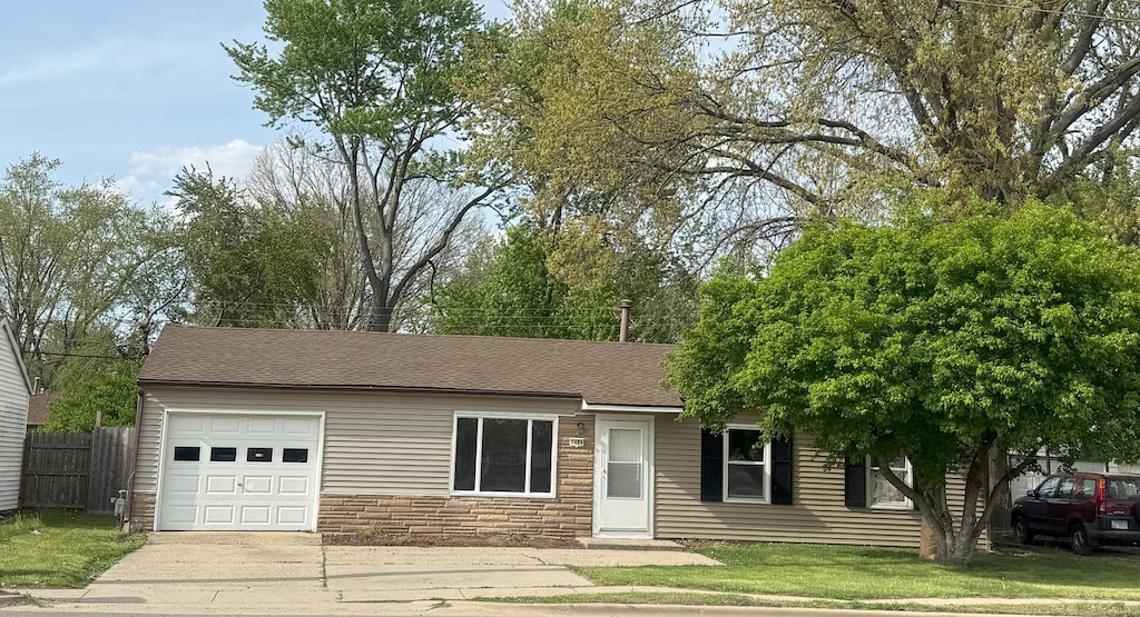 2406 W Kirby Ave, Champaign, IL 61821 - ranch-style home with an attached garage, fence, stone siding, concrete driveway, and roof with shingles