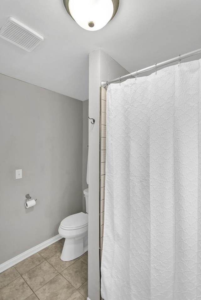 bathroom featuring curtained shower, toilet, visible vents, baseboards, and tile patterned flooring