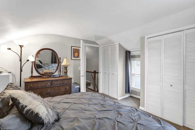 bedroom featuring two closets, baseboards, vaulted ceiling, and carpet floors