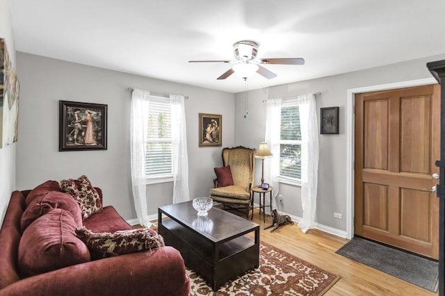 living room featuring a healthy amount of sunlight, baseboards, ceiling fan, and light wood-style flooring