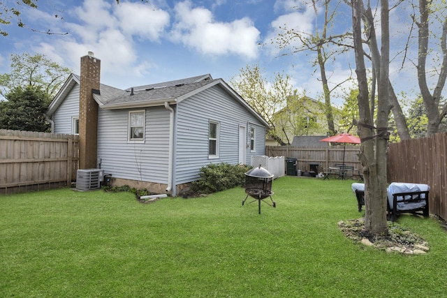 back of house with a chimney, a fenced backyard, a yard, roof with shingles, and cooling unit