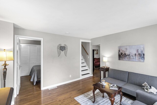 living area featuring visible vents, stairway, wood finished floors, and baseboards