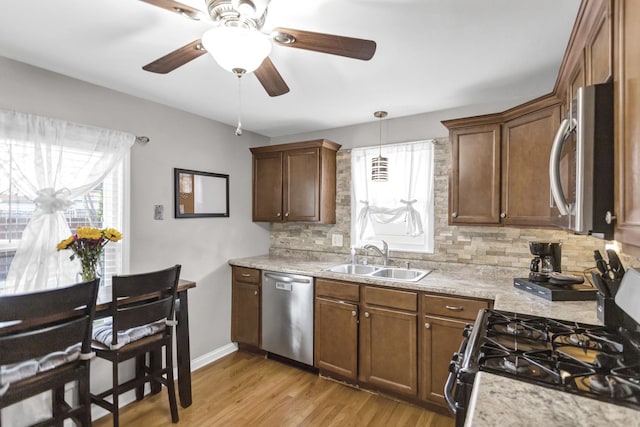 kitchen featuring tasteful backsplash, a sink, appliances with stainless steel finishes, light wood-type flooring, and a ceiling fan
