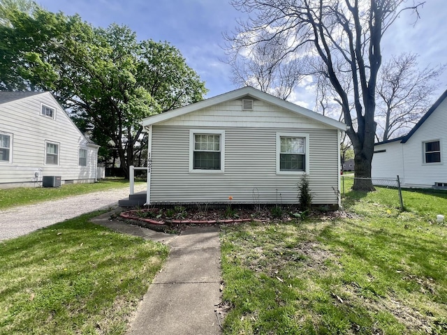 view of front facade with cooling unit, a front yard, and fence