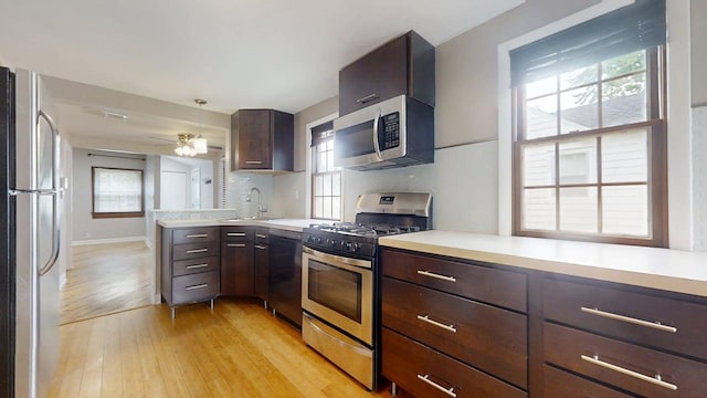 kitchen featuring appliances with stainless steel finishes, plenty of natural light, a sink, light countertops, and light wood-type flooring