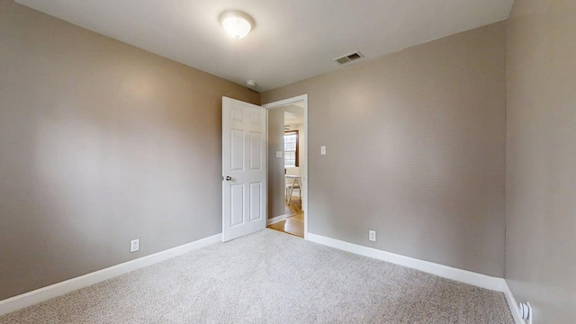spare room with carpet floors, baseboards, and visible vents
