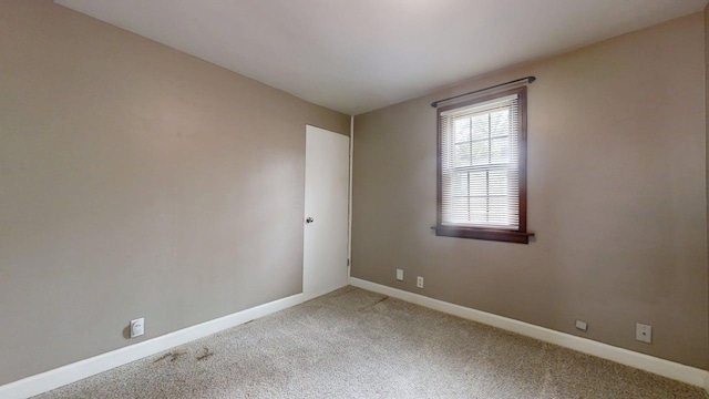 carpeted spare room featuring baseboards