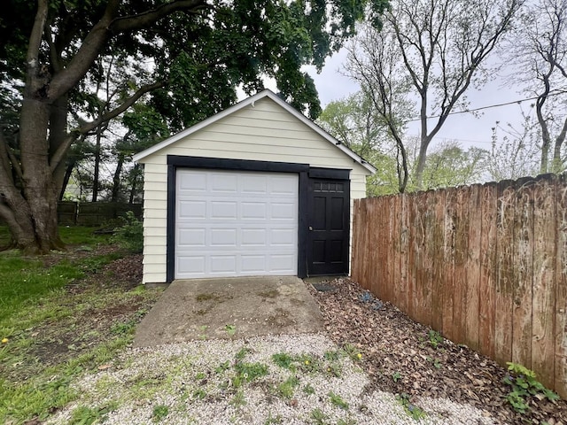 detached garage featuring driveway and fence