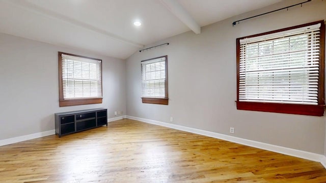 spare room featuring baseboards, vaulted ceiling with beams, and wood finished floors