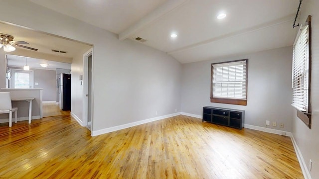 unfurnished room with lofted ceiling with beams, visible vents, light wood finished floors, a ceiling fan, and baseboards
