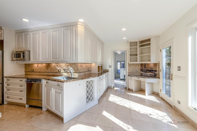 kitchen with a sink, decorative backsplash, dark stone countertops, open shelves, and appliances with stainless steel finishes