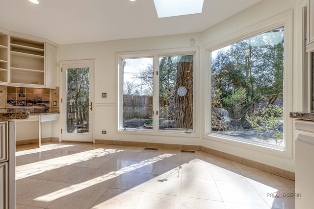 interior space featuring baseboards, visible vents, a skylight, and plenty of natural light