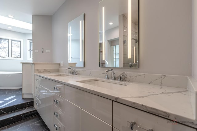 bathroom featuring recessed lighting, double vanity, a sink, and a freestanding bath